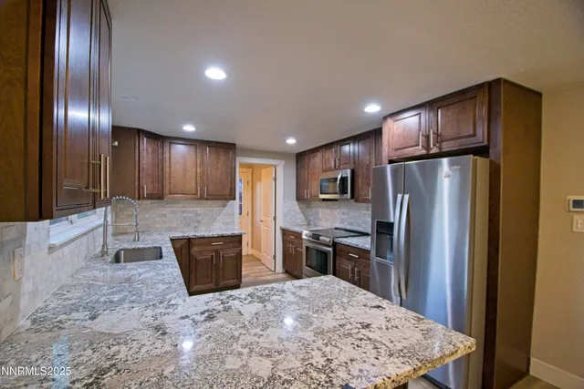 a kitchen with stainless steel appliances granite countertop wooden cabinets a refrigerator and a sink