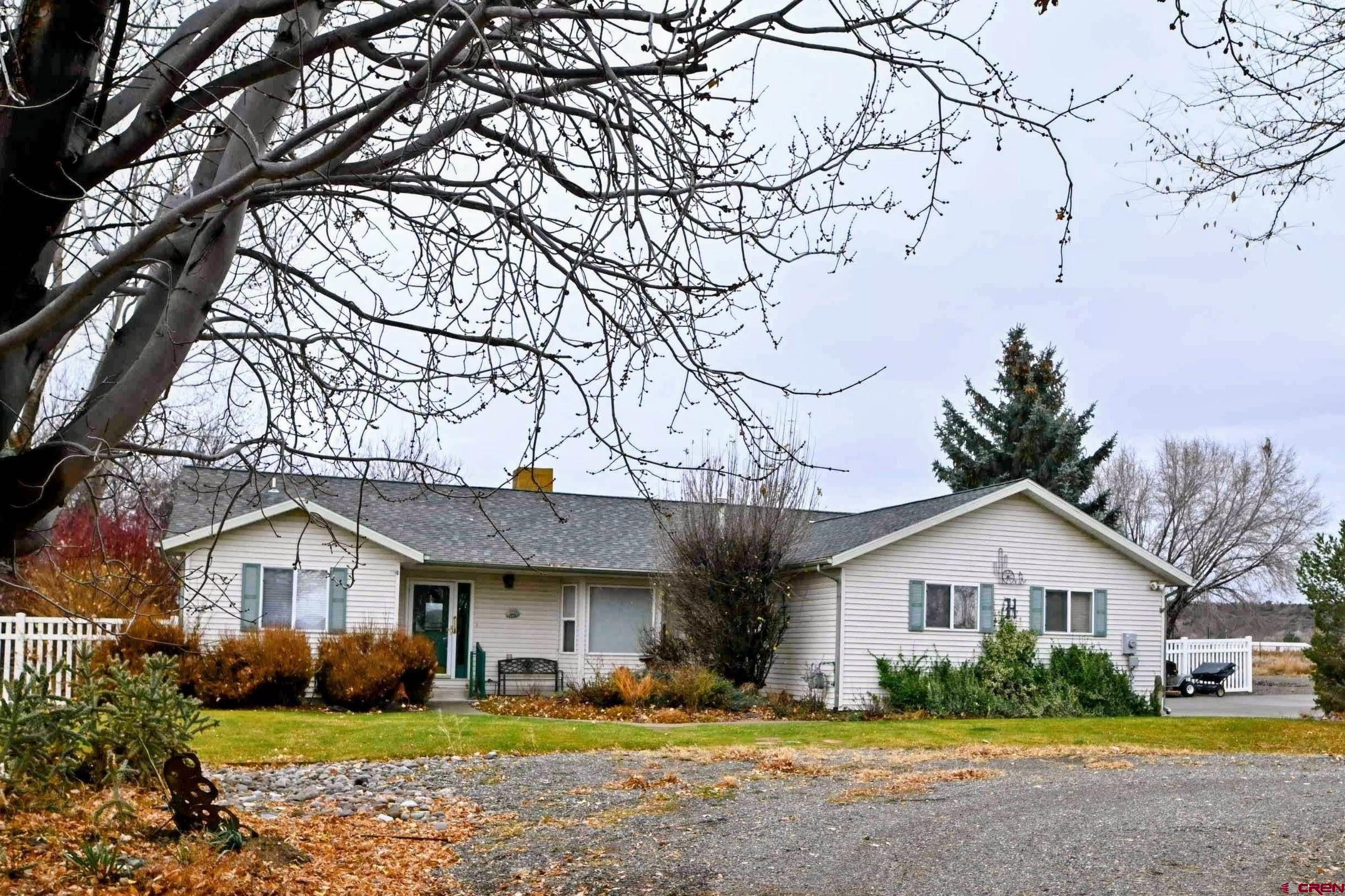 66750 Solar Road Montrose, CO 81403 - Photo 11 of 45 a front view of a house with a garden and trees