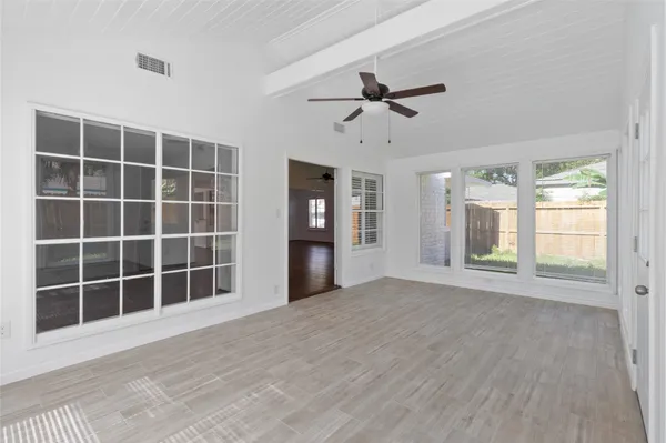 a view of an empty room with a window and wooden floor