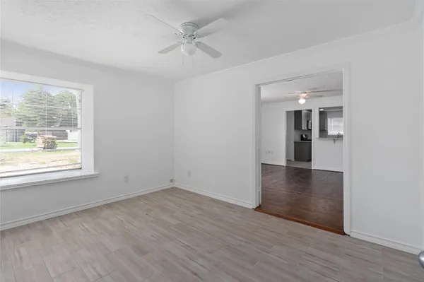 a view of an empty room with wooden floor and a window