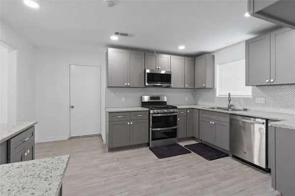 a kitchen with granite countertop a stove top oven a sink dishwasher and a refrigerator