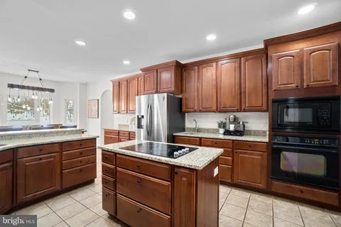 a living room with stainless steel appliances furniture a rug kitchen view and a chandelier
