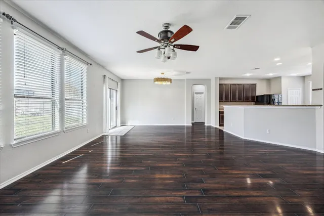 a view of an empty room with kitchen and window