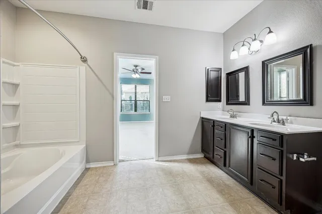 a spacious bathroom with a tub double sink and mirror