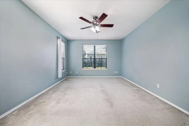 an empty room with a window and a fan
