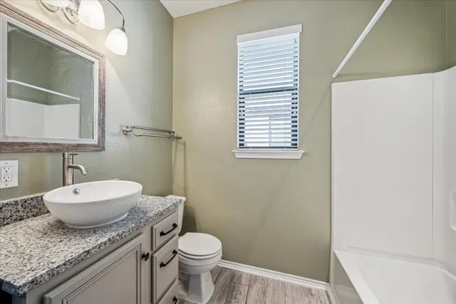 a bathroom with a granite countertop sink mirror vanity and toilet