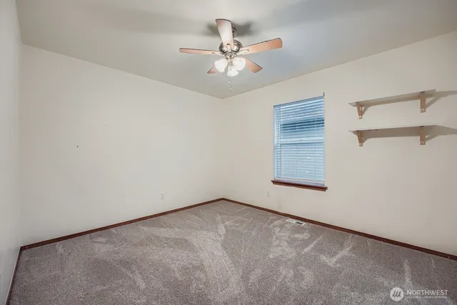 an empty room with a ceiling fan and a window