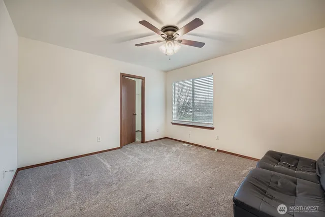 an empty room with windows and ceiling fan