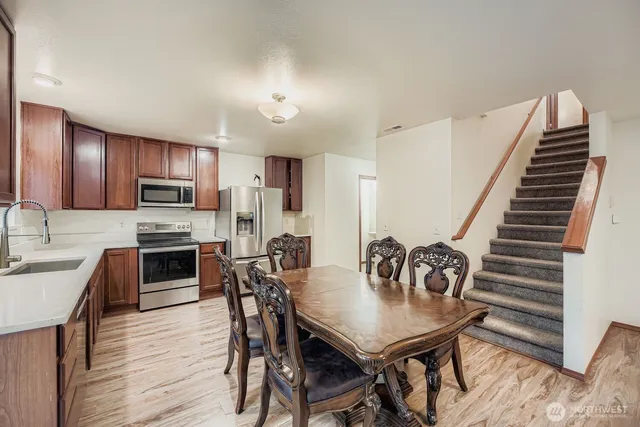 a kitchen with granite countertop stainless steel appliances cabinets a dining table and chairs