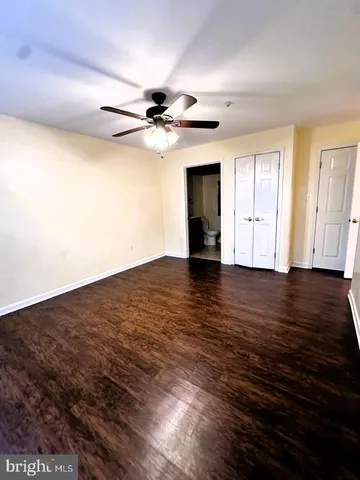 a view of an empty room with wooden floor and a ceiling fan