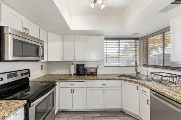 a kitchen with granite countertop cabinets stainless steel appliances a sink and window