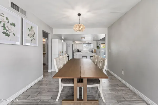 a dining room with wooden floor a chandelier a wooden table and chairs