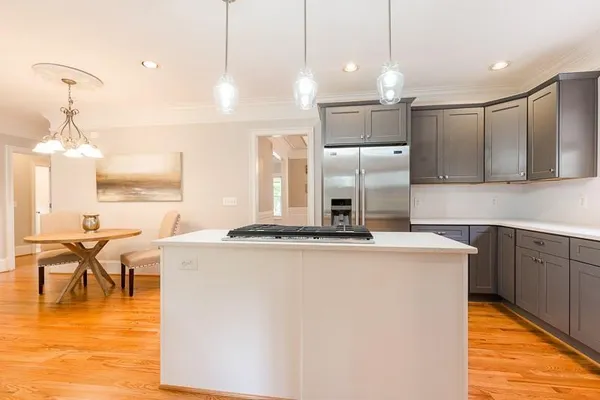 a kitchen with kitchen island a stove a refrigerator a sink dishwasher with a dining table and chairs with wooden floor