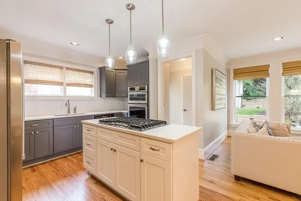 a kitchen with a stove a sink a center island and windows