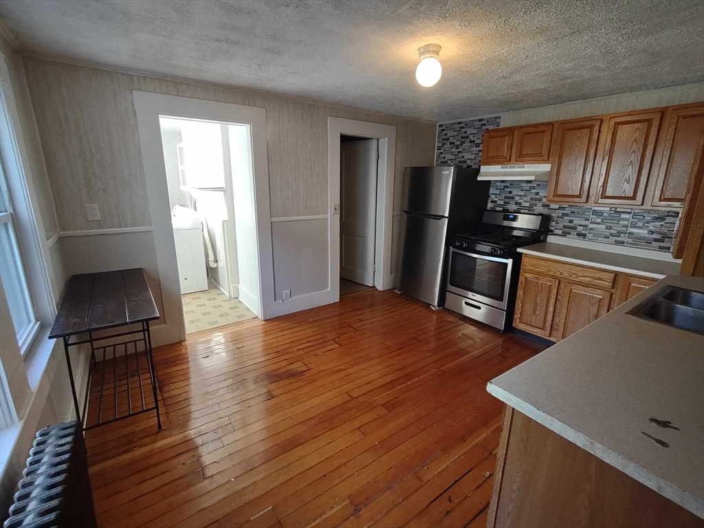 16 Kilby Street, Unit 3 Woburn, MA 01801 - Photo 2 of 12 a kitchen with stainless steel appliances wooden floor window and wooden cabinets