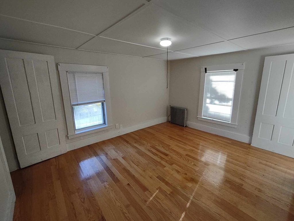 16 Kilby Street, Unit 3 Woburn, MA 01801 - Photo 9 of 12 an empty room with wooden floor and windows