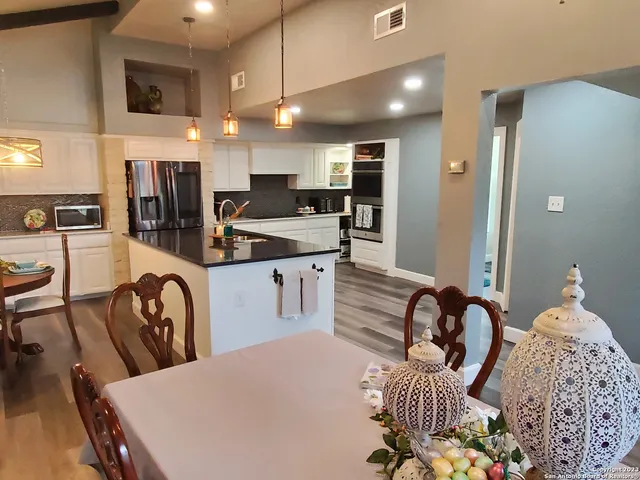 a kitchen with stainless steel appliances kitchen island granite countertop a sink a refrigerator and chairs