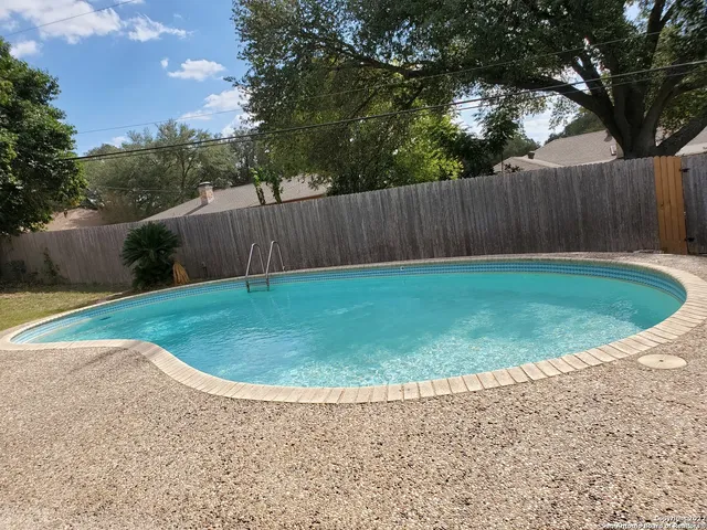 a view of a backyard with a small deck and wooden fence