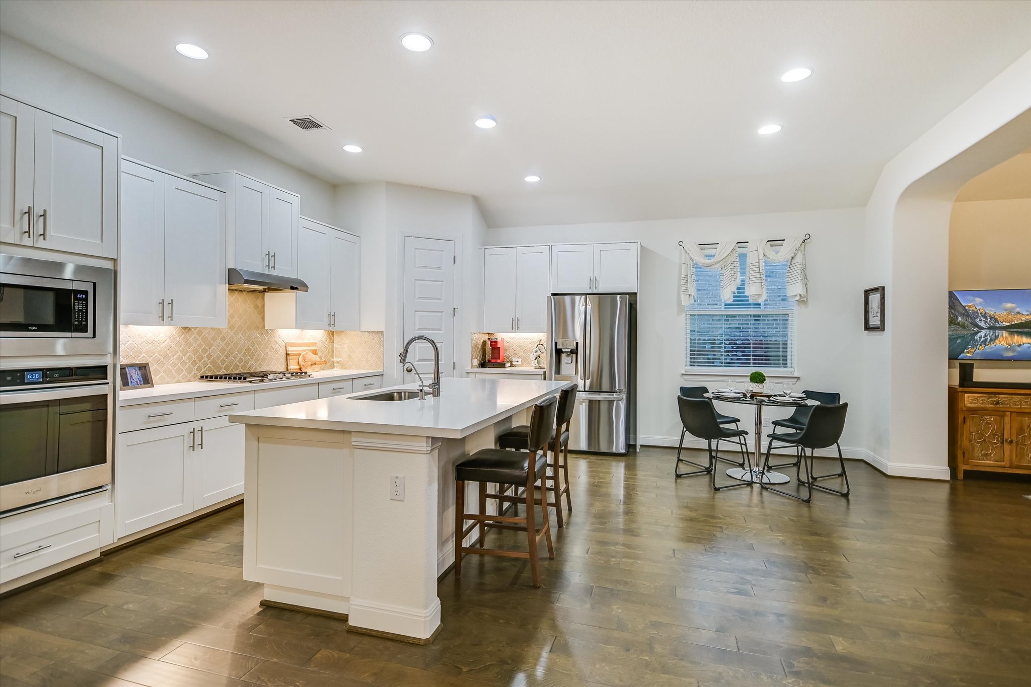 508 Peakside Circle Dripping Springs, TX 78620 - Photo 14 of 30 Kitchen featuring stainless steel appliances, a kitchen island with sink, recessed lighting, a kitchen breakfast bar, and white cabinets
