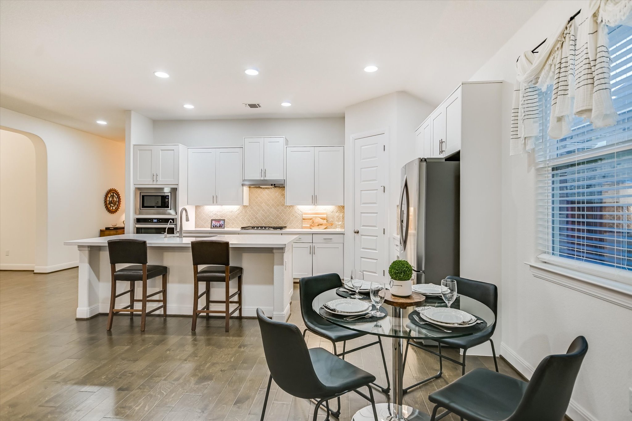 508 Peakside Circle Dripping Springs, TX 78620 - Photo 16 of 30 Kitchen featuring arched walkways, a kitchen breakfast bar, an island with sink, white cabinets, and light wood-style flooring