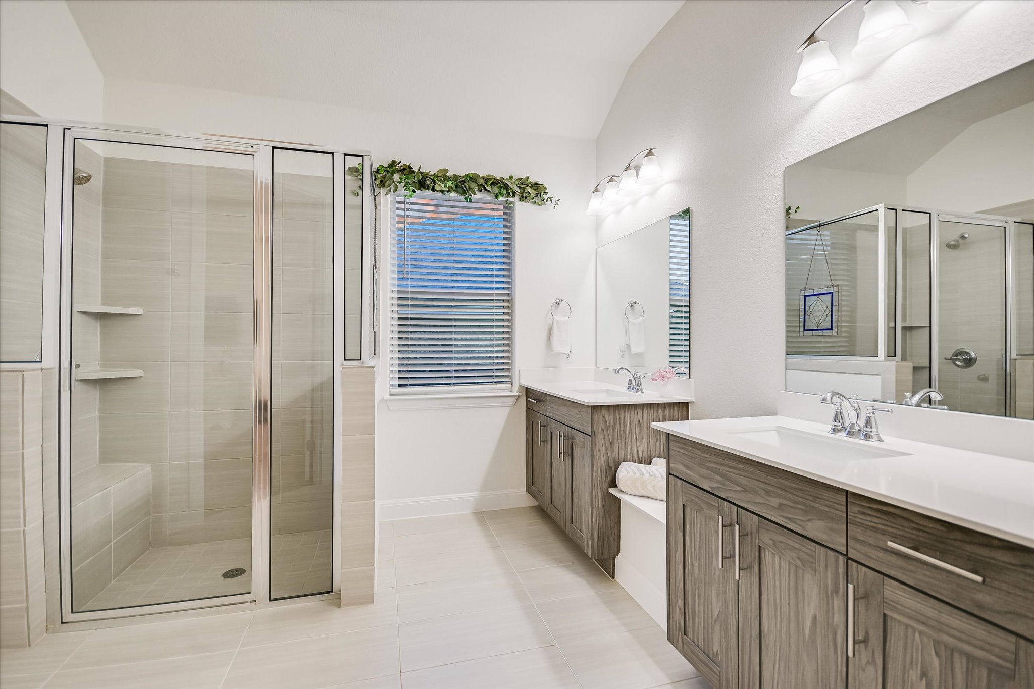 508 Peakside Circle Dripping Springs, TX 78620 - Photo 21 of 30 Bathroom featuring two vanities, a stall shower, light tile patterned floors, and vaulted ceiling