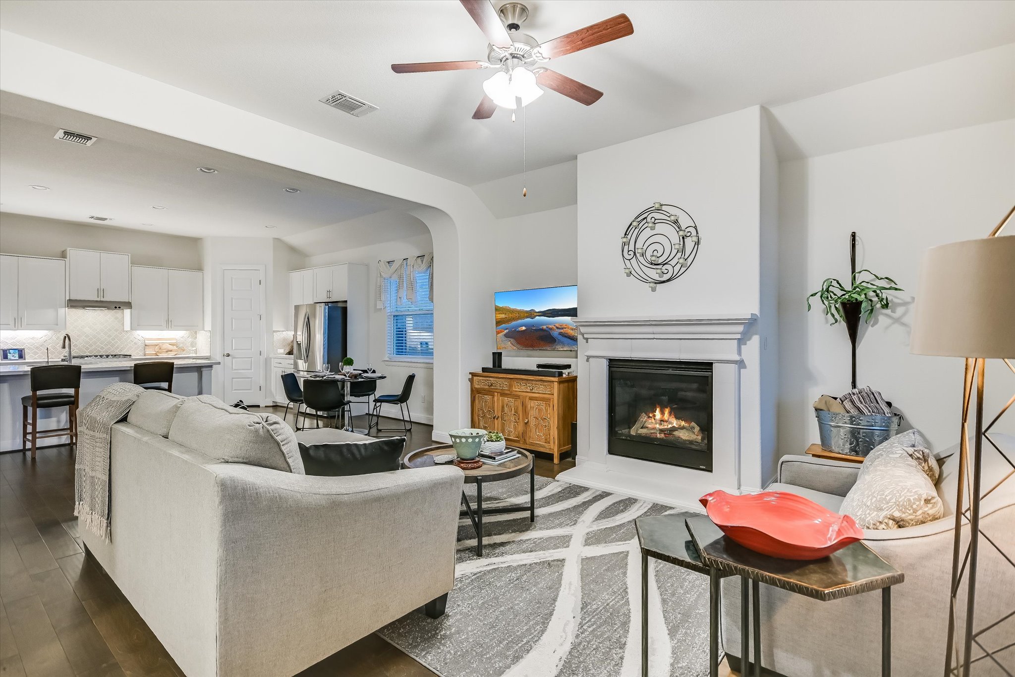 508 Peakside Circle Dripping Springs, TX 78620 - Photo 9 of 30 Living area with ceiling fan, dark wood finished floors, a glass covered fireplace, and arched walkways