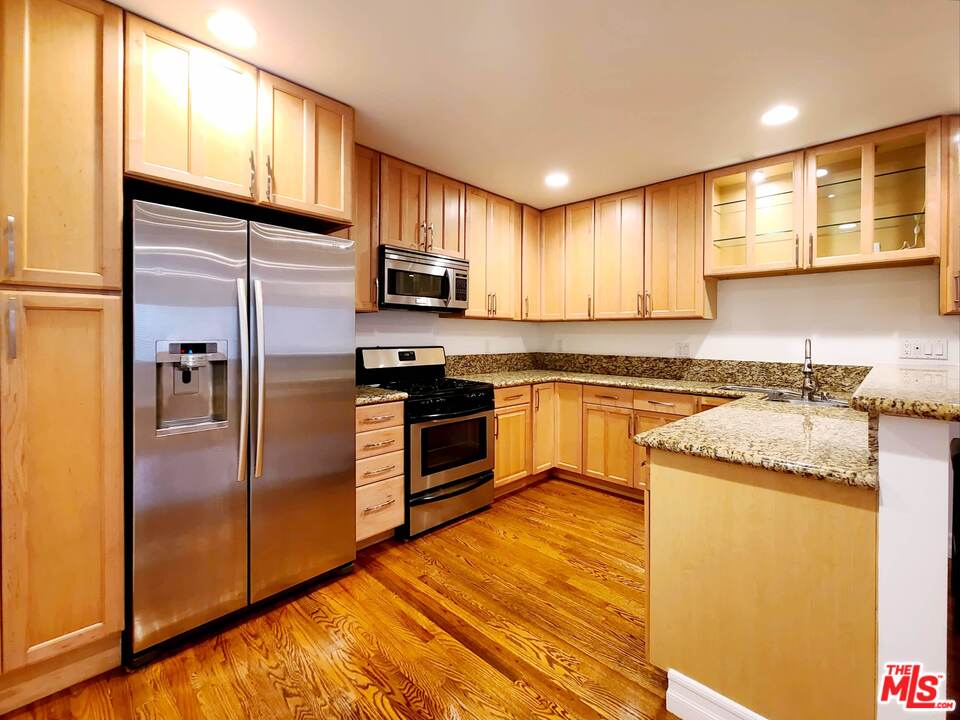 a kitchen with granite countertop wooden floors stainless steel appliances and window