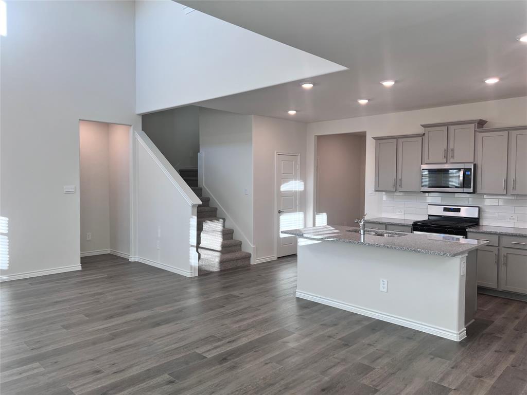 10313 Rambling Brks Lane Aubrey, TX 76227 - Photo 7 of 17 a kitchen with granite countertop a stove and a wooden floor