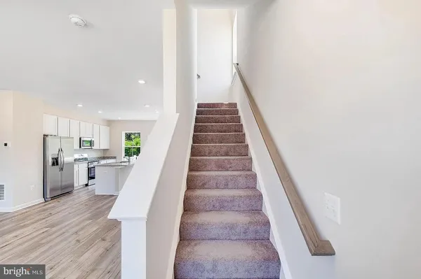 a kitchen with stainless steel appliances a sink a stove a microwave a refrigerator and cabinets