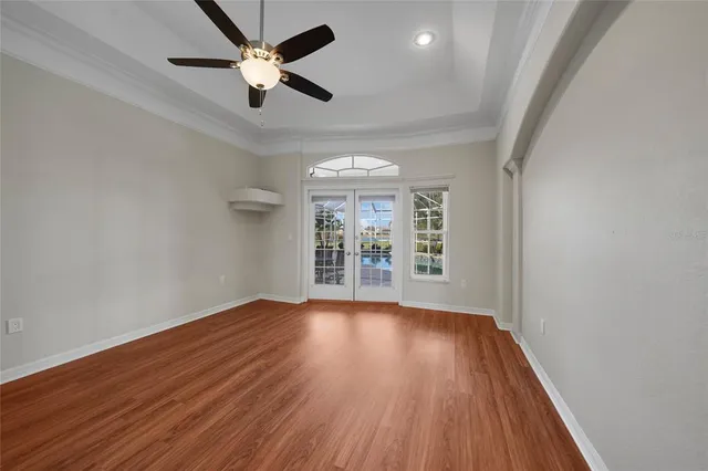 an empty room with wooden floor fan and windows