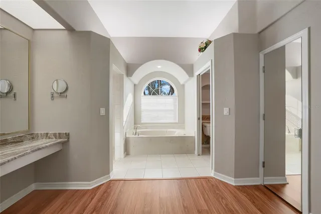 a view of an empty room with wooden floor and a ceiling fan