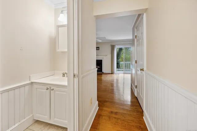 a view of a hallway with wooden floor and a bathroom