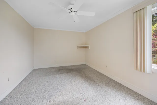 an empty room with a window and a ceiling fan