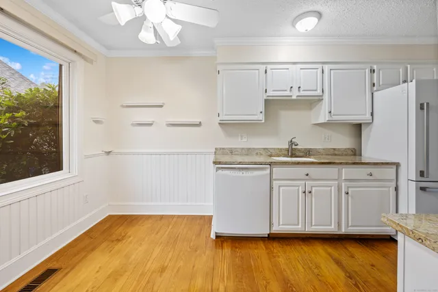 a kitchen with granite countertop white cabinets and wooden floor