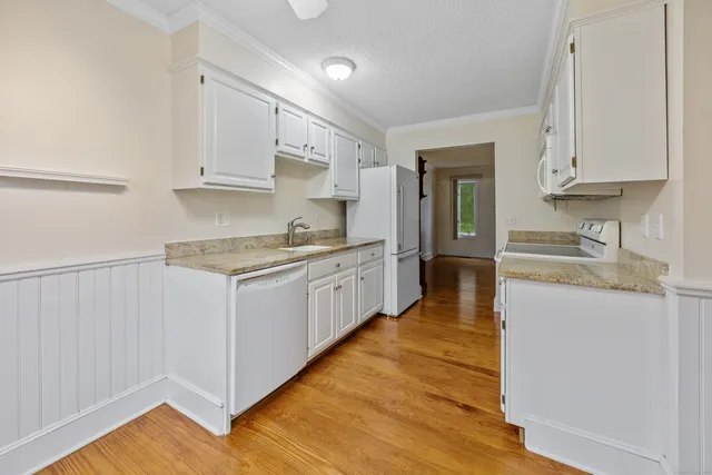 a kitchen with granite countertop white cabinets and white appliances