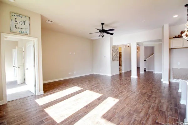 a view of an empty room with a window and kitchen view