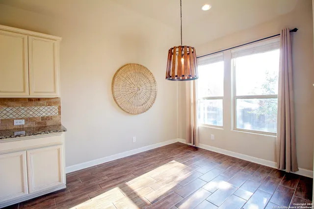 a backyard of a house with table and chairs plants and large tree