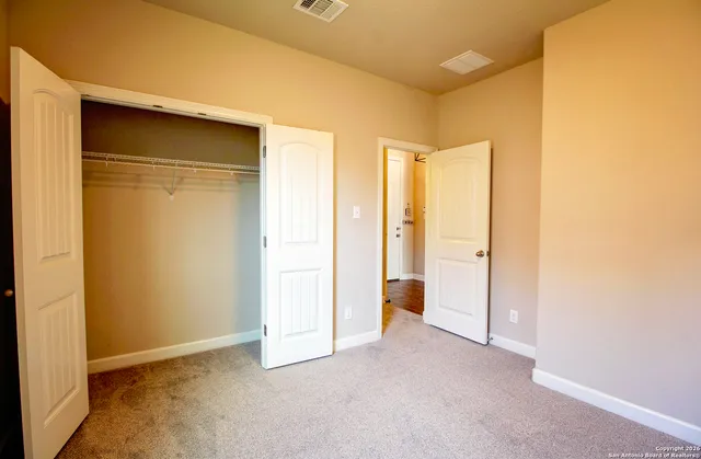 a view of an empty room with glass door and wooden floor