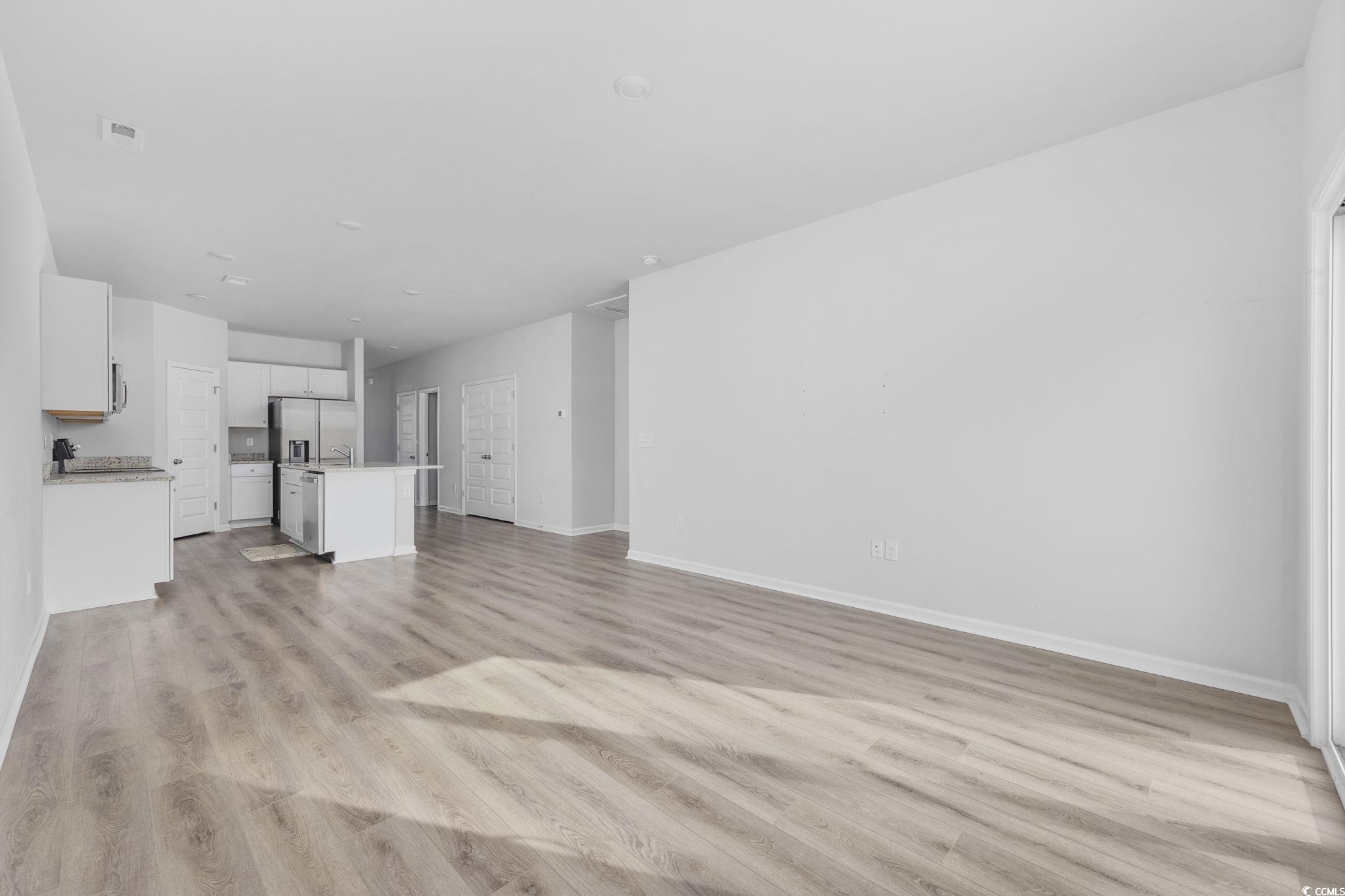 608 Sea Sparrow Street, Unit 608 Myrtle Beach, SC 29588 - Photo 11 of 37 Unfurnished living room featuring light wood-style floors and baseboards