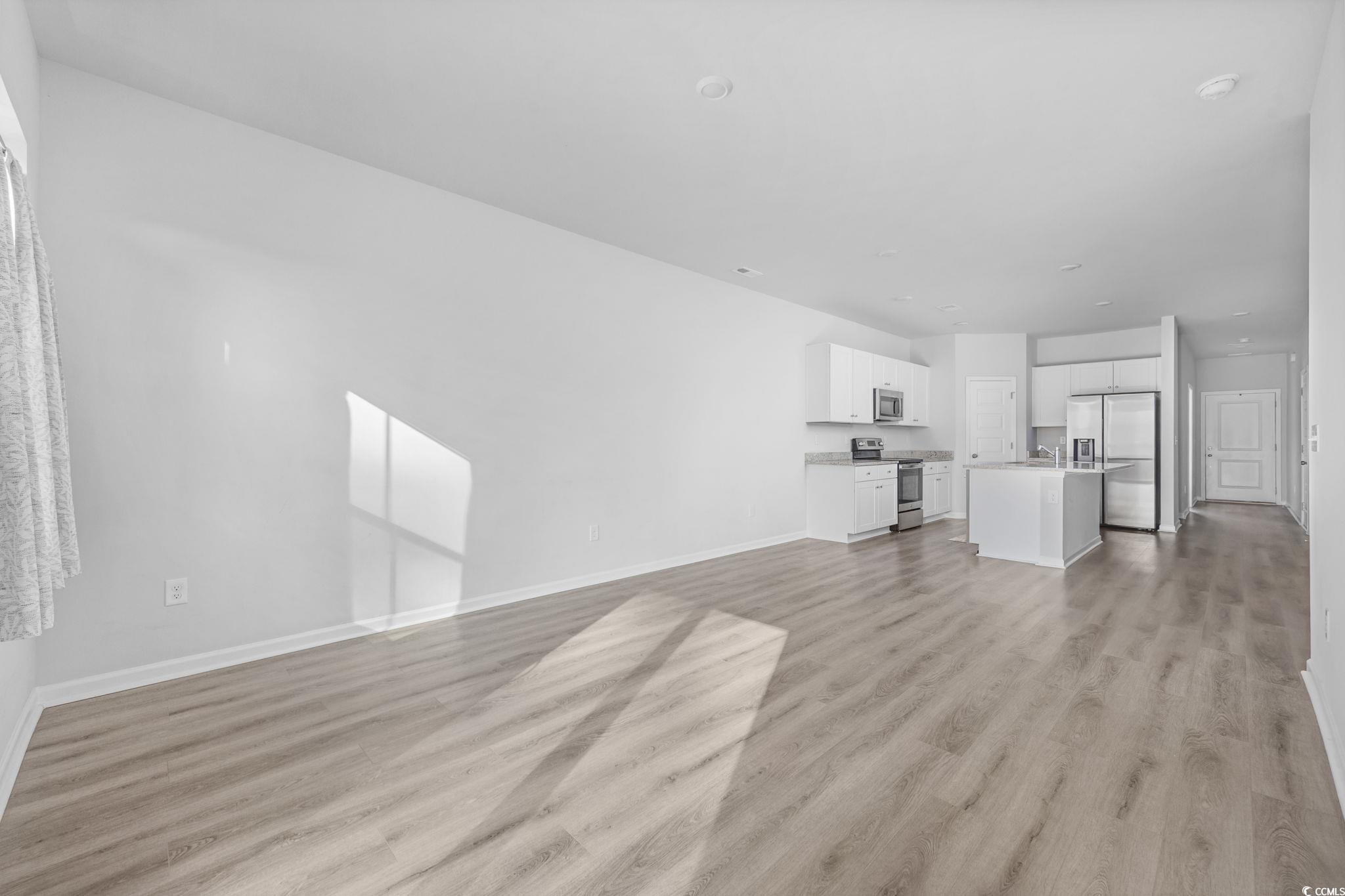 608 Sea Sparrow Street, Unit 608 Myrtle Beach, SC 29588 - Photo 12 of 37 Unfurnished living room featuring light wood-style floors and baseboards
