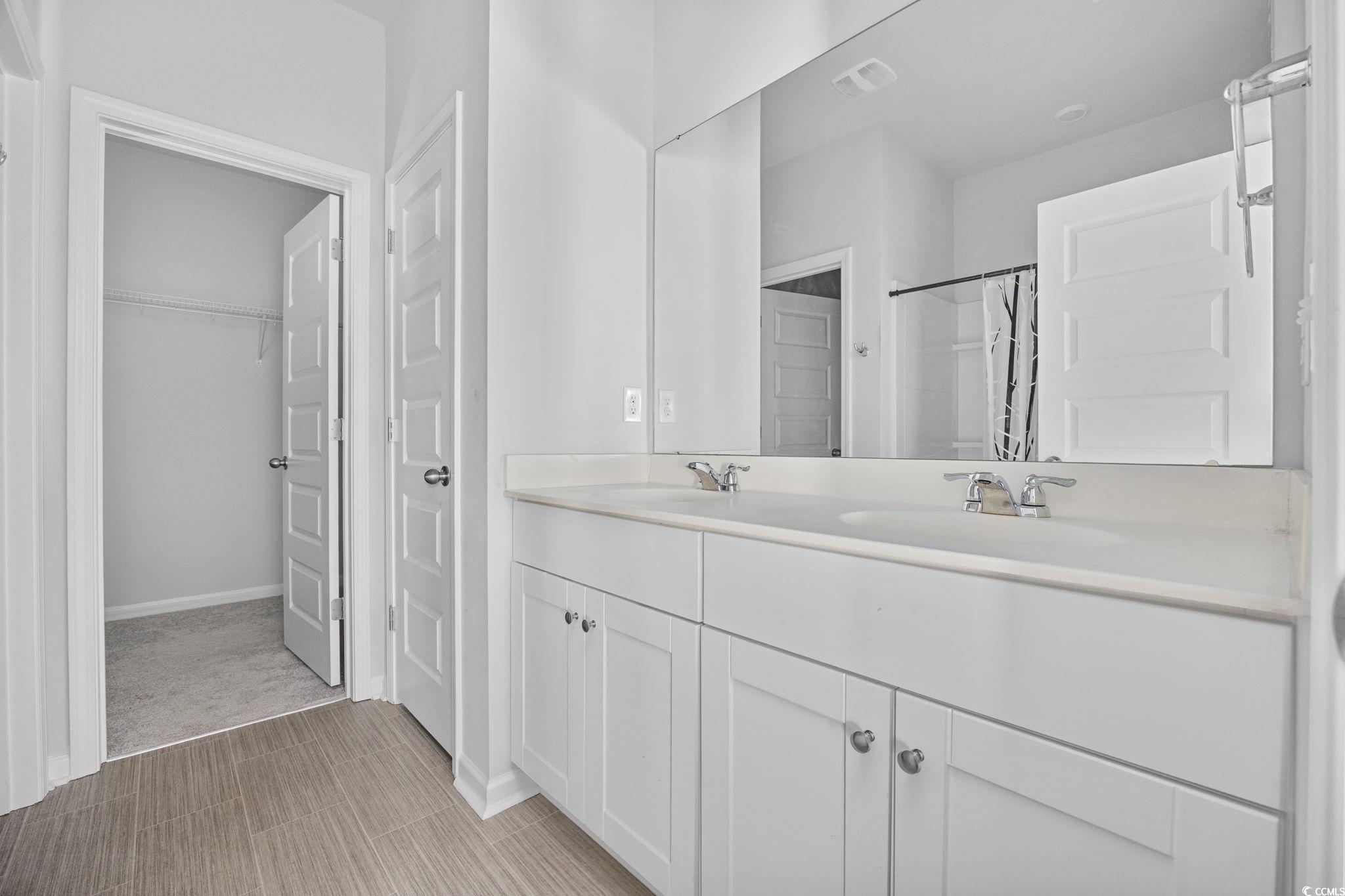 608 Sea Sparrow Street, Unit 608 Myrtle Beach, SC 29588 - Photo 16 of 37 Bathroom with double vanity, a shower with curtain, and a spacious closet