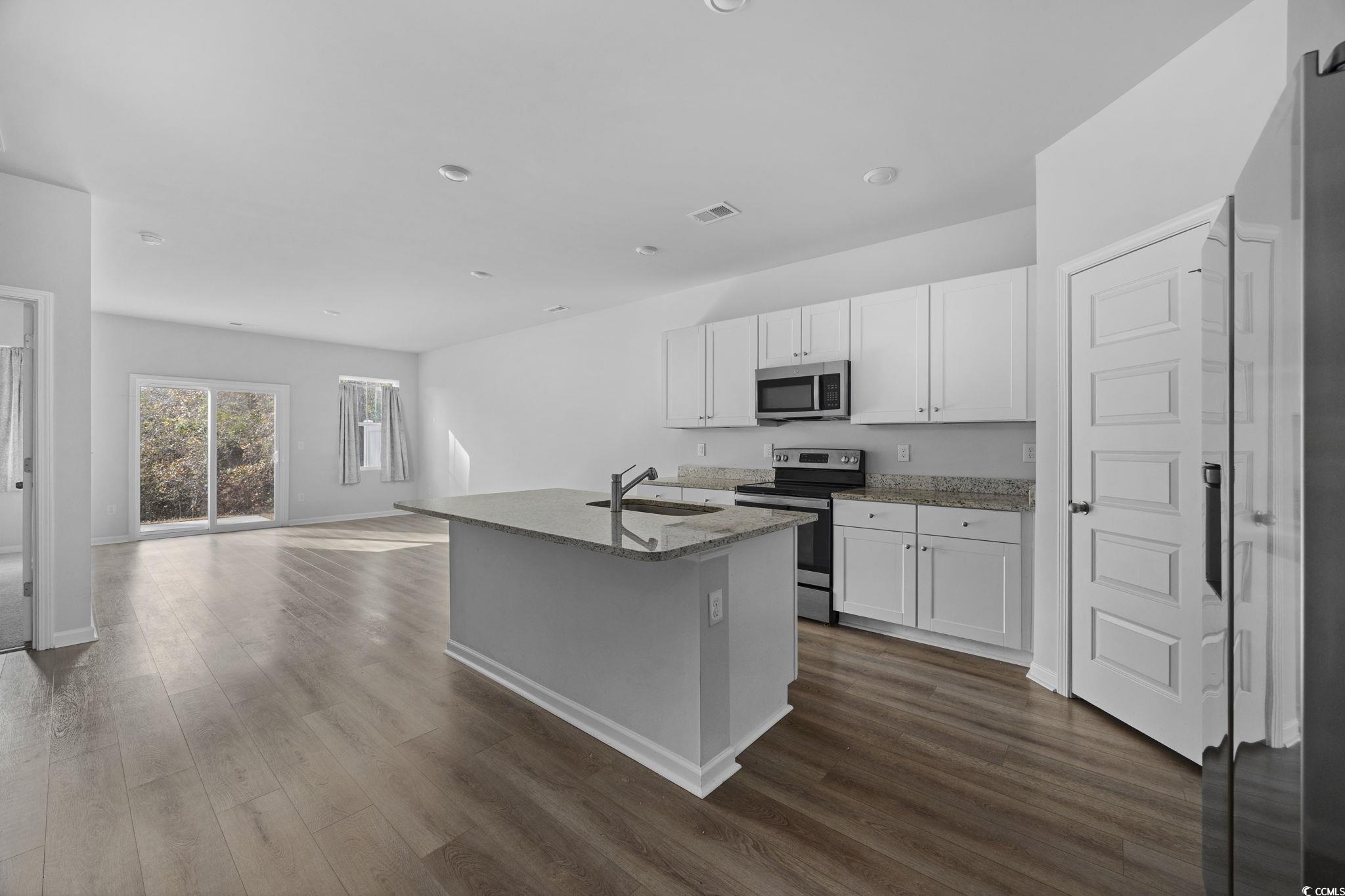 608 Sea Sparrow Street, Unit 608 Myrtle Beach, SC 29588 - Photo 2 of 37 Kitchen featuring stainless steel appliances, a kitchen island with sink, white cabinetry, light stone countertops, and dark wood finished floors