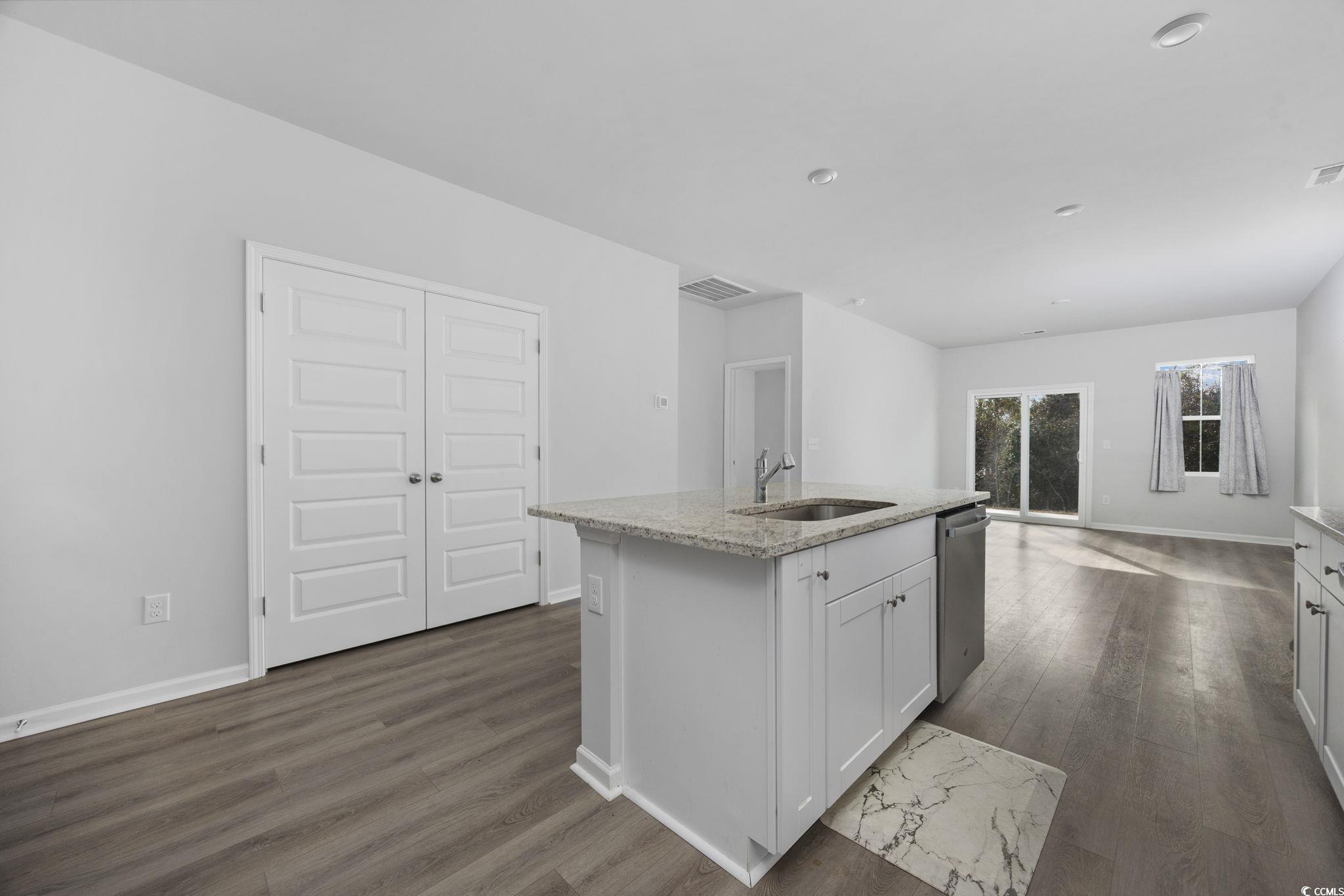608 Sea Sparrow Street, Unit 608 Myrtle Beach, SC 29588 - Photo 9 of 37 Kitchen with white cabinetry, light stone countertops, a kitchen island with sink, dark wood finished floors, and stainless steel dishwasher