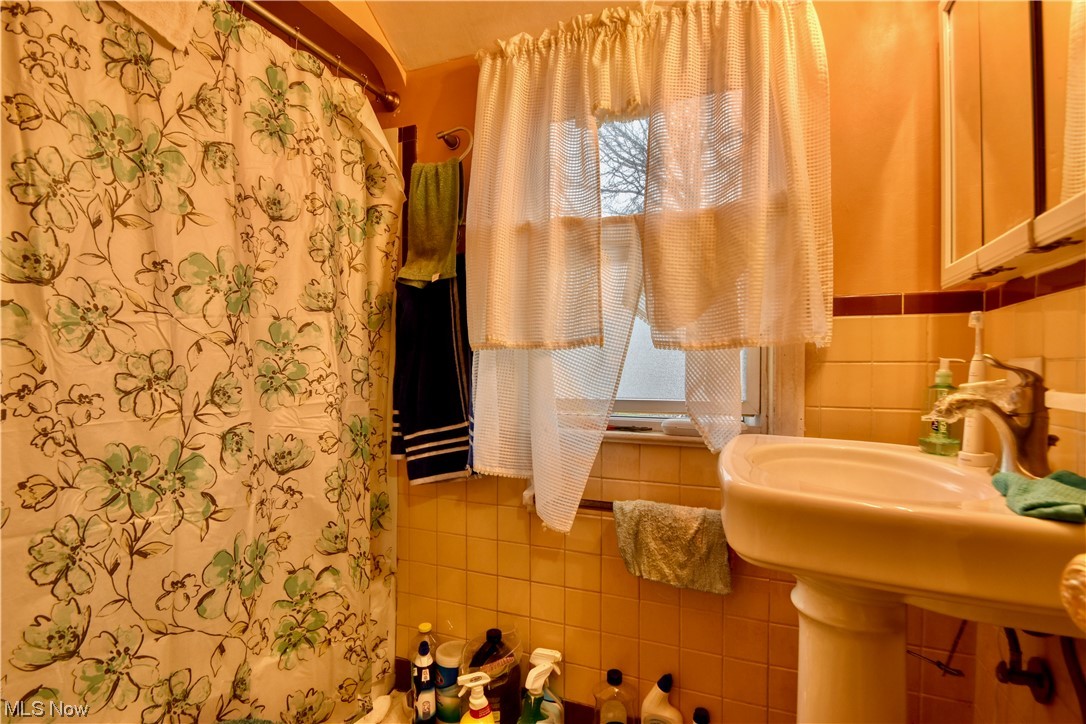 1659 Catalpa Road Cleveland, OH 44112 - Photo 13 of 21 Bathroom featuring sink, tile walls, and backsplash