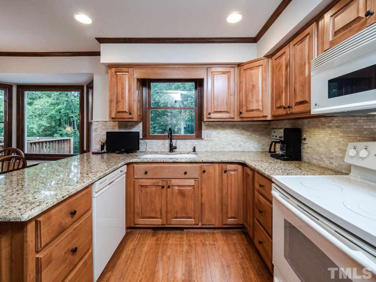 7705 Valley Run Drive Raleigh, NC 27615 - Photo 4 of 27 a kitchen with stainless steel appliances granite countertop wooden cabinets a sink and a large window