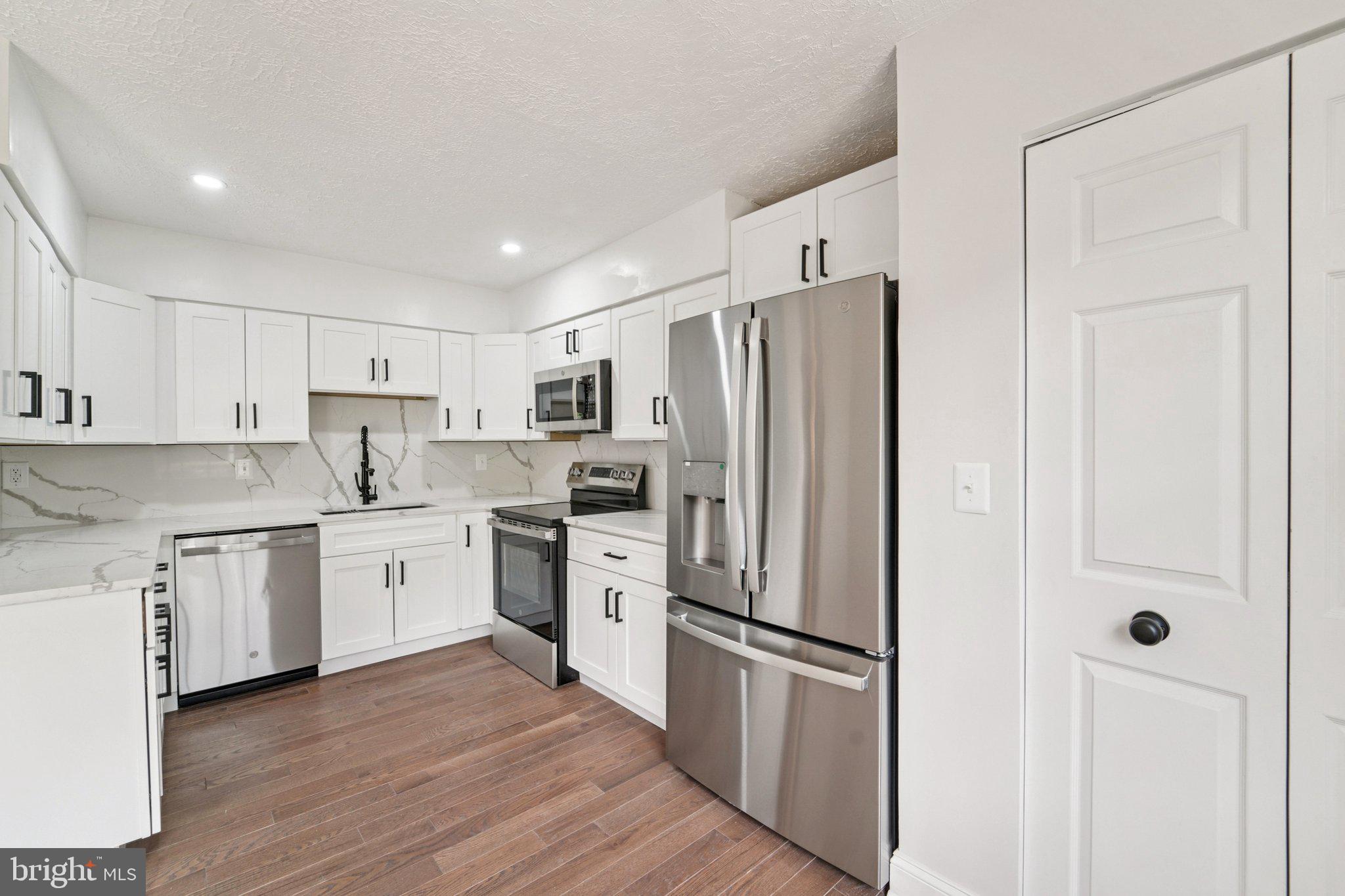 8727 Silver Hall Road Perry Hall, MD 21128 - Photo 8 of 35 a kitchen with stainless steel appliances a refrigerator a sink and white cabinets