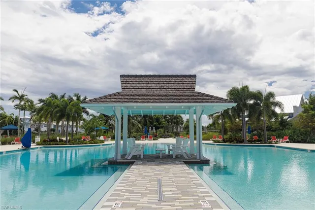 a view of swimming pool with lawn chairs and plants