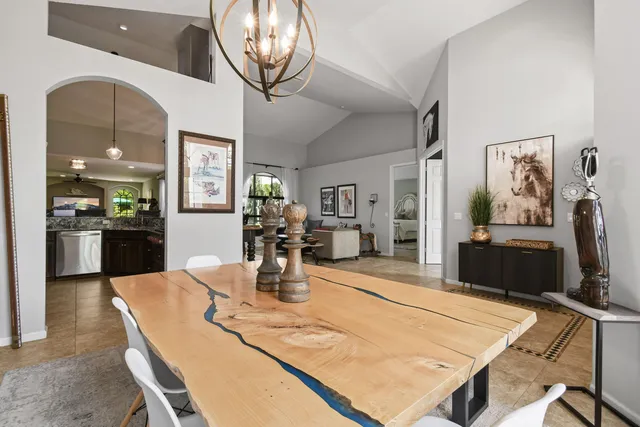 a dining room with wooden floor a chandelier a wooden table and chairs