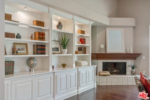 a living room with stainless steel appliances furniture a fireplace and cabinets