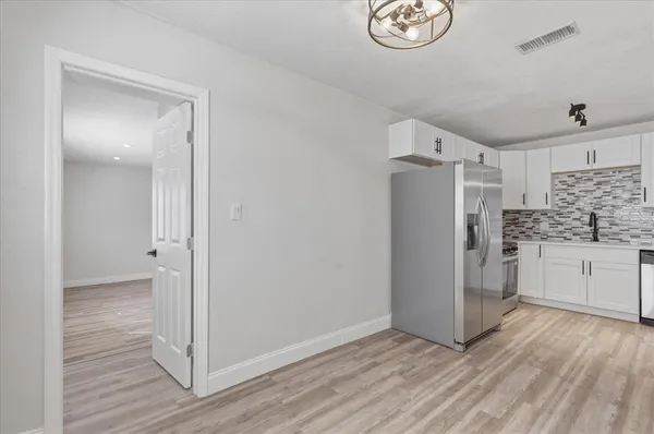 a view of kitchen with refrigerator cabinets and wooden floor